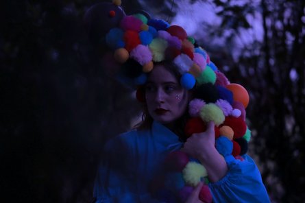 2026-03-20 Fete Galante Person mit bunter Perücke aus Kugeln in der Dämmerung