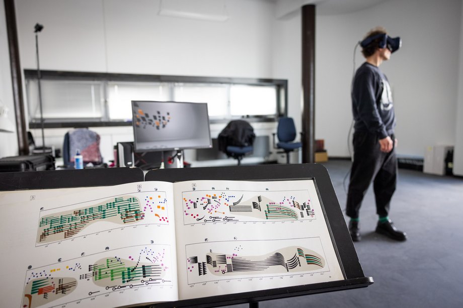 Notenständer im Vordergrund und Person mit 3D-Bille im Hintergrund