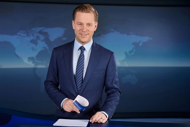 2026-03-19 Helge Fuhlst Ein lächelnder Mann in Anzug und Krawatte in einem Nachrichtenstudio