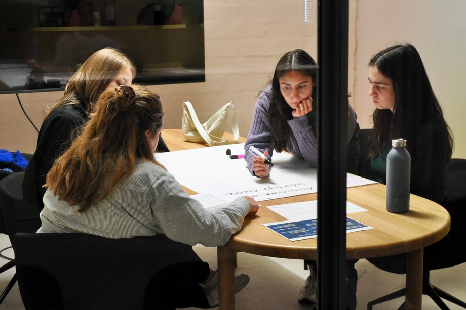 KMM Präsenzstudium Vier Studierende beim Gespräch an einem Tisch