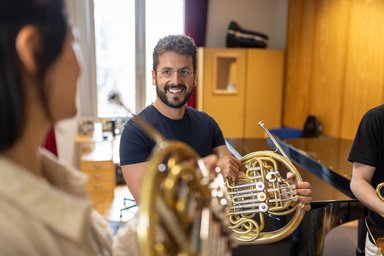 3 Personen mit Horn in der Hand in Kommunikation miteinander