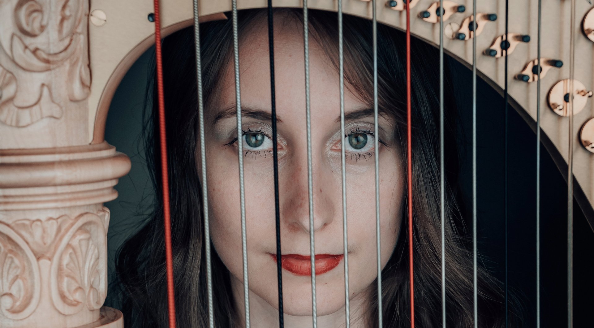 Chiara Sax blickt durch die Saiten ihrer Harfe in die Kamera