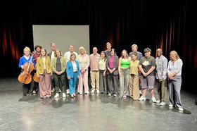 Viele Menschen stehen für ein Gruppenfoto auf einer Theaterbühne