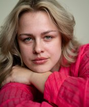Portraitfoto einer blonden Frau mit rotem Pullover.