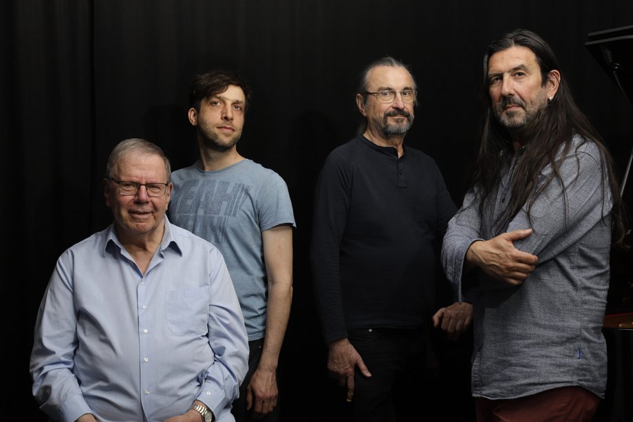 Group photo of four men in front of a black background