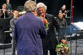 Gratulation für Ulrich Windfuhr Mann bekommt einen Brumenstrauß auf einer Bühne überreicht